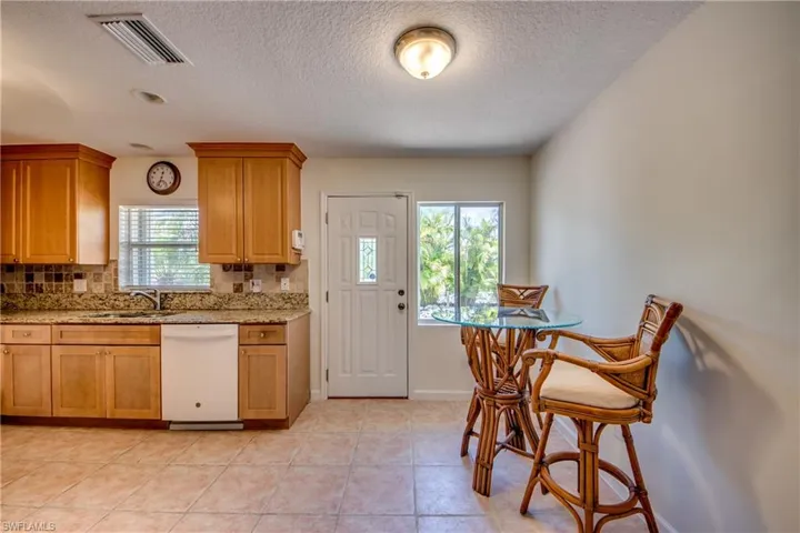Kitchen featuring a healthy amount of sunlight, decorative backsplash, white dishwasher, and light tile patterned floors