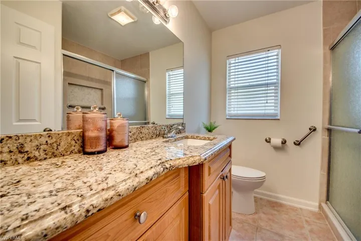 Bathroom featuring tile patterned flooring, a shower with door, toilet, and vanity