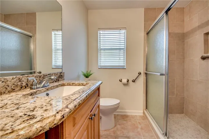 Bathroom with vanity, walk in shower, tile patterned flooring, and toilet