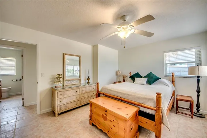 Tiled bedroom with a textured ceiling, ceiling fan, and connected bathroom