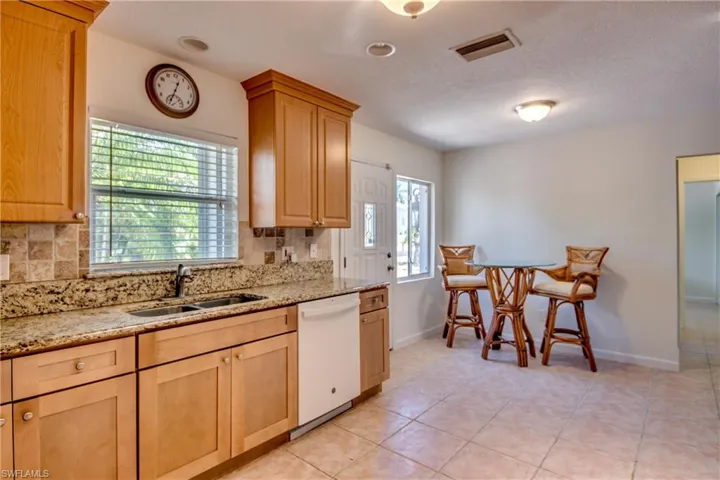 Kitchen with sink, white dishwasher, light tile patterned floors, and backsplash