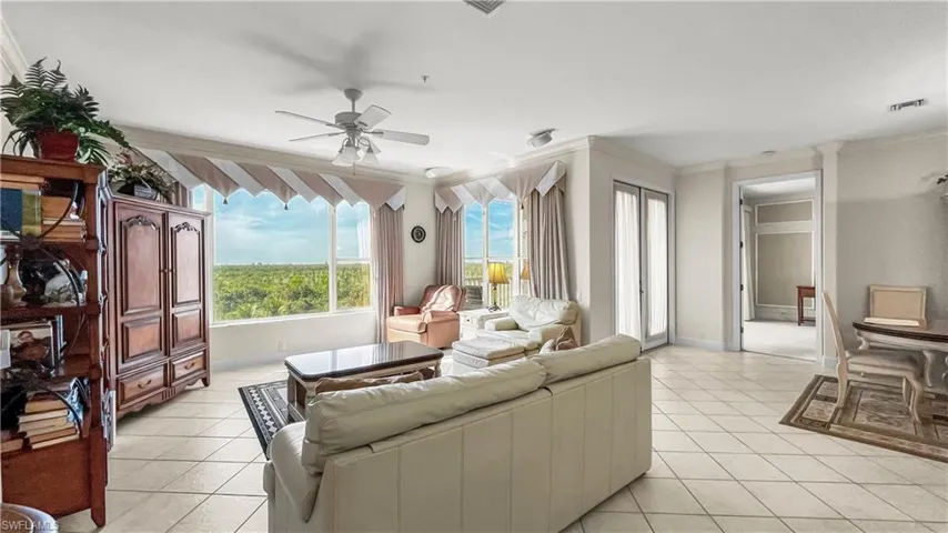 Living room featuring ceiling fan, crown molding, and light tile patterned flooring