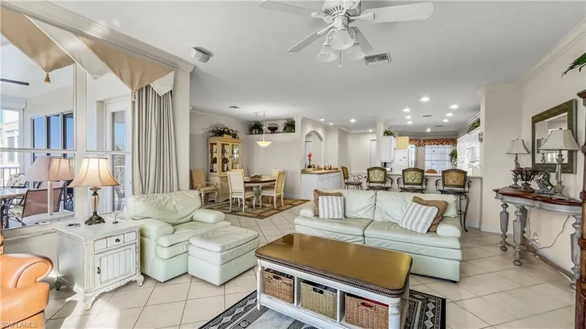 Tiled living room featuring plenty of natural light, ceiling fan, and crown molding