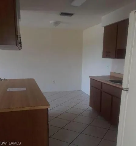 Kitchen with freestanding refrigerator, light tile patterned floors, and light countertops