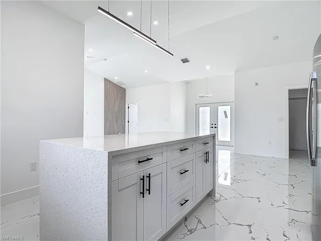 Kitchen featuring french doors, light marble finish floors, recessed lighting, white cabinetry, and light stone countertops