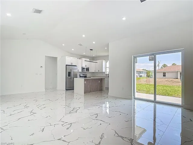Unfurnished living room with lofted ceiling, light marble finish flooring, and recessed lighting