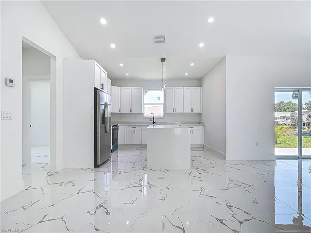 Kitchen featuring stainless steel refrigerator with ice dispenser, plenty of natural light, recessed lighting, a sink, and light countertops