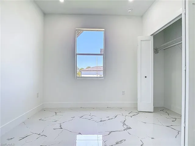 Unfurnished bedroom featuring light marble finish floors, baseboards, and recessed lighting