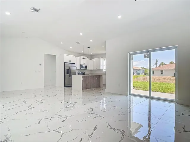 Unfurnished living room with lofted ceiling, recessed lighting, and light marble finish floors