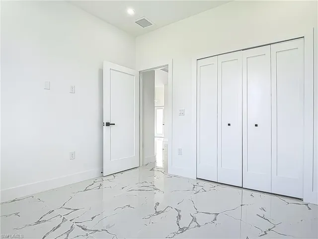 Unfurnished bedroom with light marble finish floors, baseboards, a closet, and recessed lighting