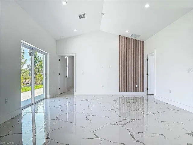 Spare room featuring light marble finish floors, recessed lighting, high vaulted ceiling, and baseboards