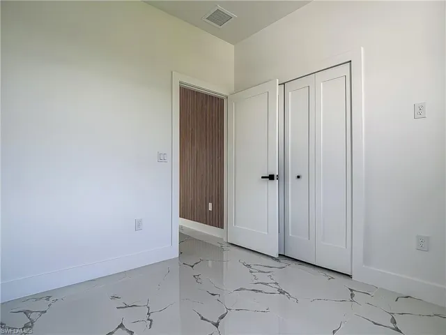 Unfurnished bedroom with light marble finish floors, baseboards, and a closet
