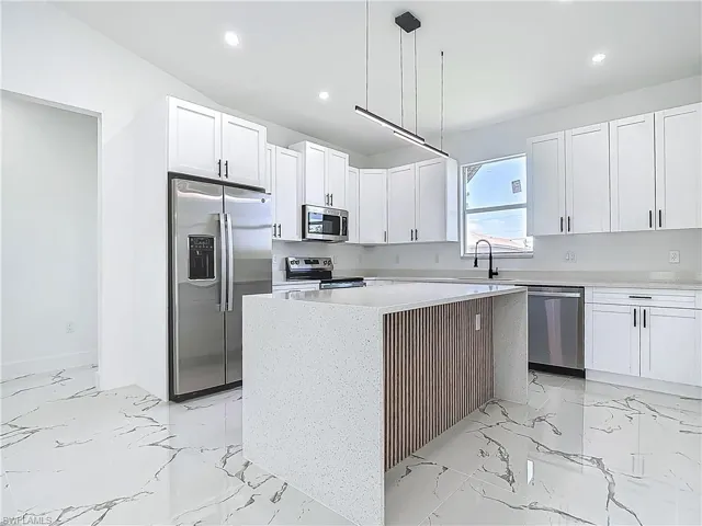 Kitchen with stainless steel appliances, recessed lighting, white cabinetry, a center island, and light countertops