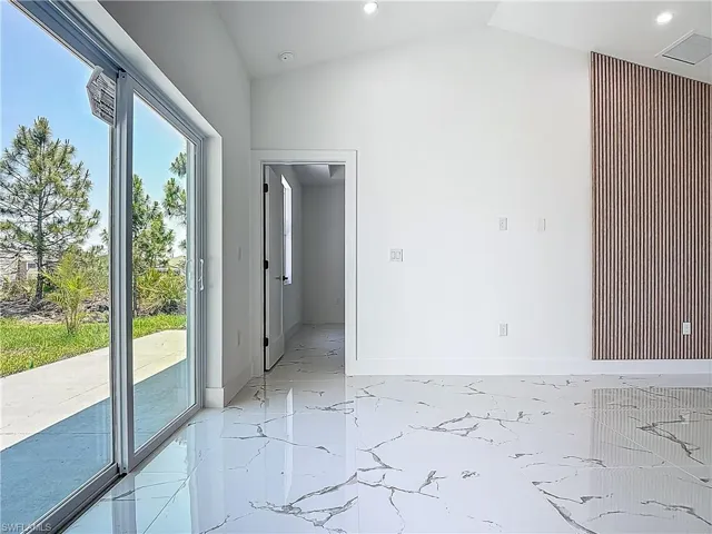 Empty room with light marble finish flooring, vaulted ceiling, baseboards, and recessed lighting
