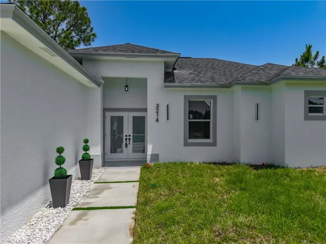 Doorway to property featuring french doors, roof with shingles, and stucco siding