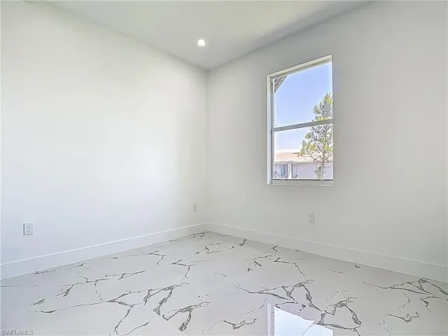 Spare room with baseboards, recessed lighting, and light marble finish floors
