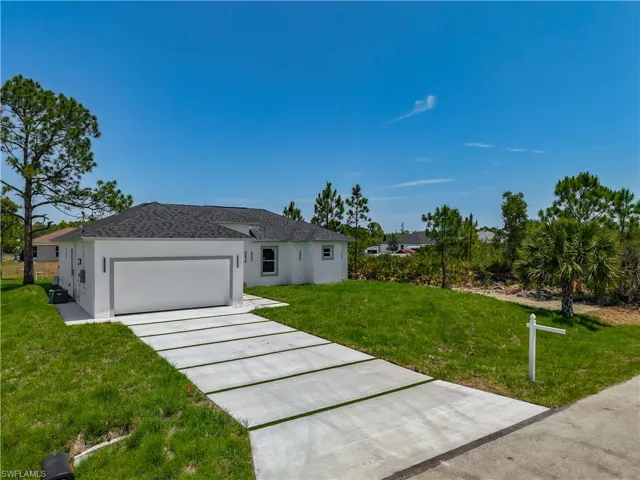 Single story home featuring a front lawn, an attached garage, driveway, and stucco siding