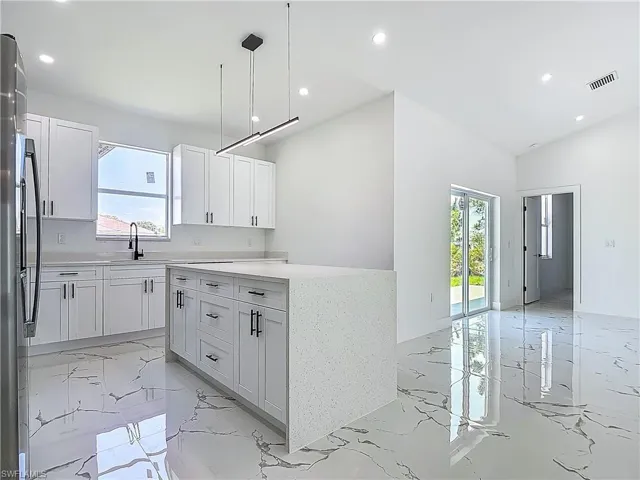 Kitchen featuring light marble finish flooring, plenty of natural light, a sink, recessed lighting, and white cabinets