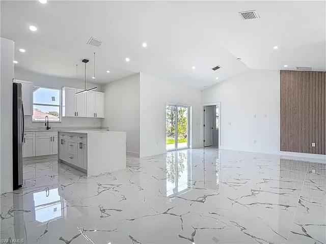 Kitchen with light marble finish floors, open floor plan, recessed lighting, a sink, and freestanding refrigerator