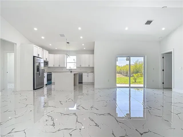 Unfurnished living room featuring light marble finish floors, recessed lighting, and a sink
