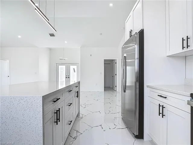 Kitchen with freestanding refrigerator, light marble finish floors, recessed lighting, light countertops, and white cabinets