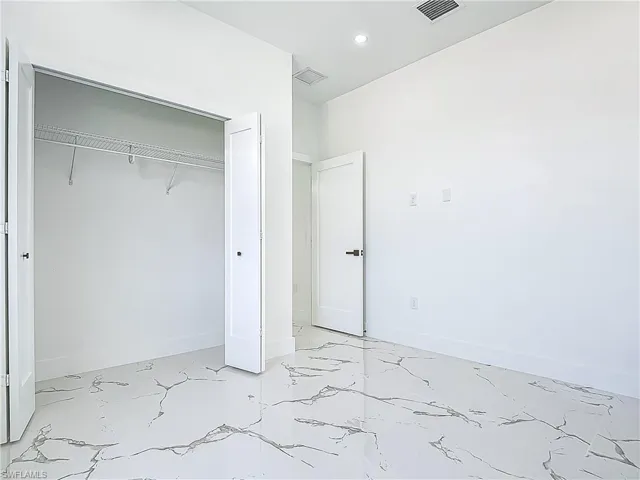 Unfurnished bedroom with light marble finish flooring, a closet, recessed lighting, and baseboards