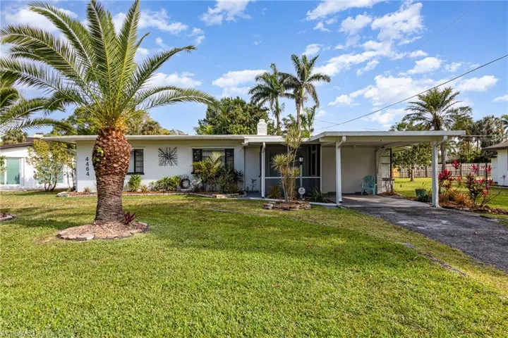Ranch-style house with driveway, an attached carport, a front lawn, and stucco siding