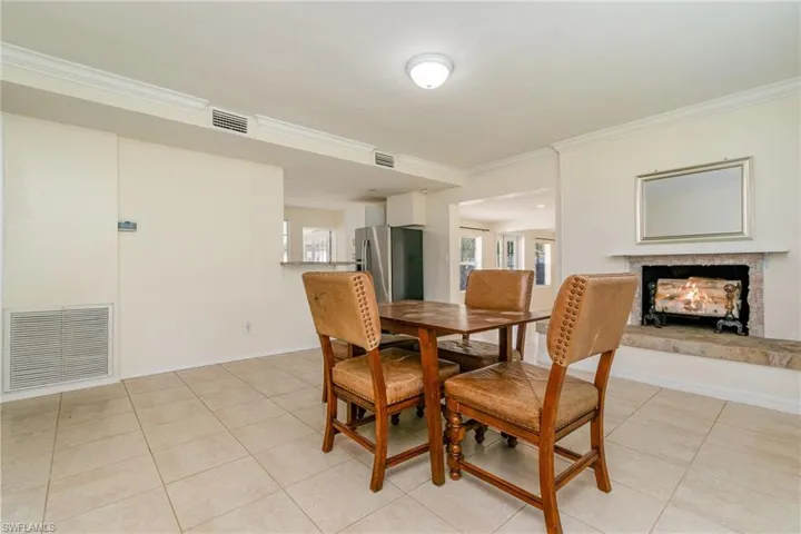 Dining space featuring a warm lit fireplace, crown molding, and visible vents