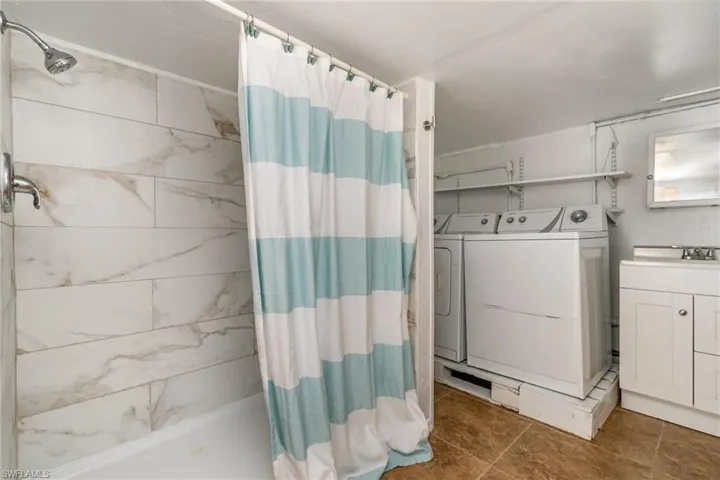 Bathroom featuring vanity, curtained shower, and washer and dryer