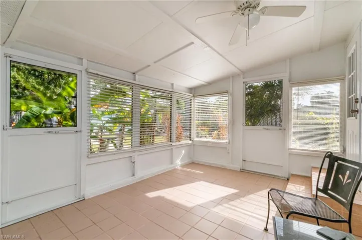 Unfurnished sunroom with a healthy amount of sunlight, lofted ceiling, and a ceiling fan