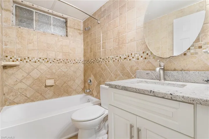 Bathroom featuring toilet, vanity, tasteful backsplash, and shower / washtub combination