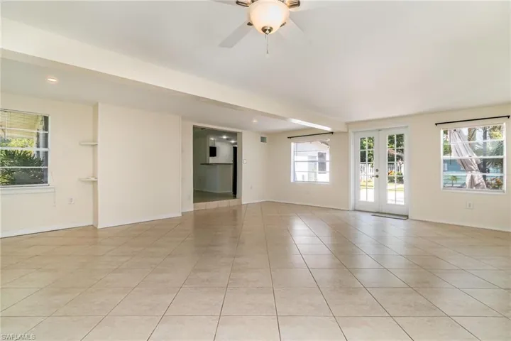 Empty room with light tile patterned flooring, baseboards, ceiling fan, recessed lighting, and french doors