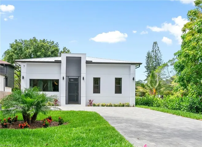 Contemporary house featuring a standing seam roof, stucco siding, a metal roof, and a front lawn