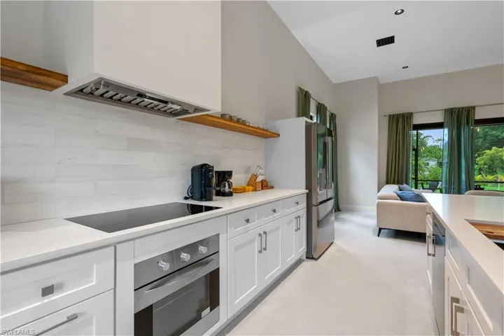 Kitchen featuring open shelves, appliances with stainless steel finishes, custom exhaust hood, backsplash, and white cabinetry