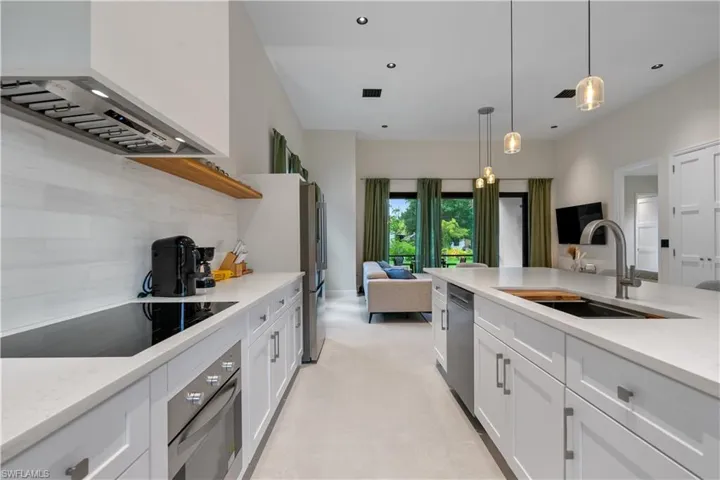 Kitchen featuring open floor plan, premium range hood, appliances with stainless steel finishes, white cabinets, and tasteful backsplash