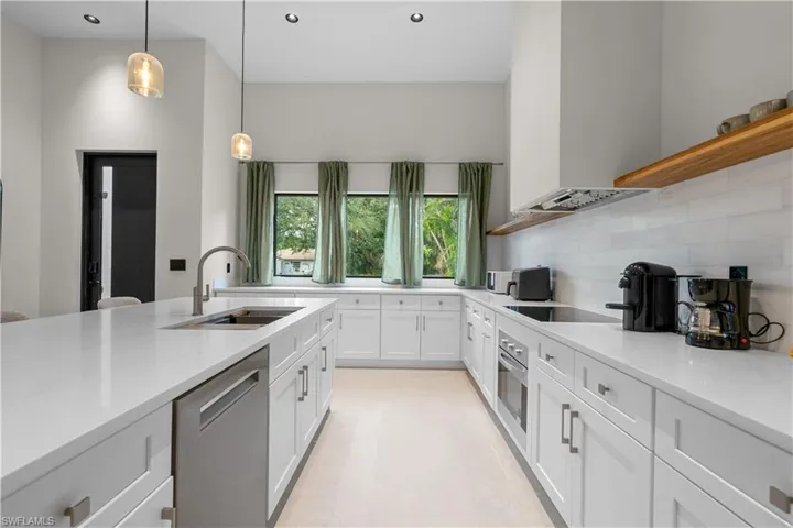 Kitchen featuring open shelves, white cabinetry, light stone countertops, stainless steel appliances, and decorative light fixtures