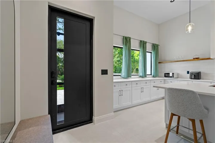 Kitchen featuring white cabinetry, a kitchen bar, pendant lighting, open shelves, and tasteful backsplash
