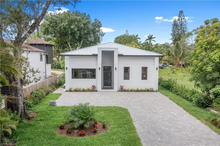 View of front of property with a front lawn, stucco siding, and decorative driveway