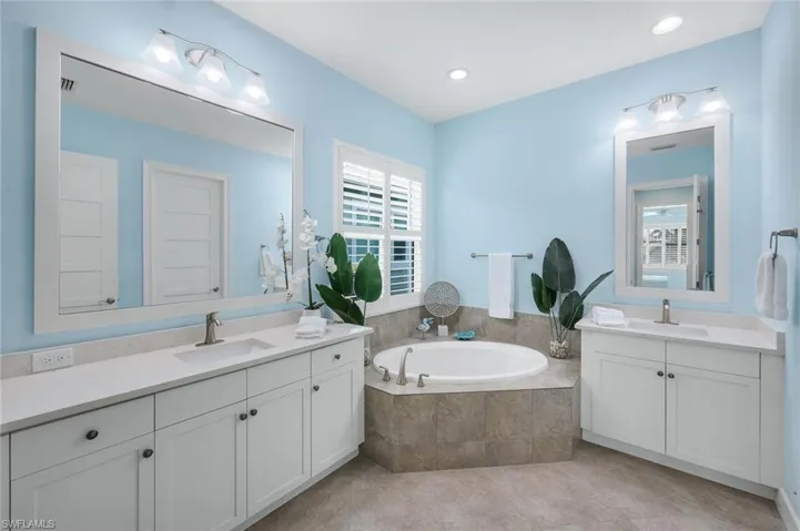 Bathroom featuring two vanities and a garden tub