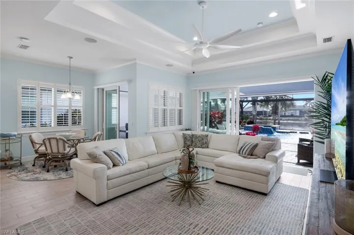 Living area featuring wood finished floors, a ceiling fan, recessed lighting, and ornamental molding