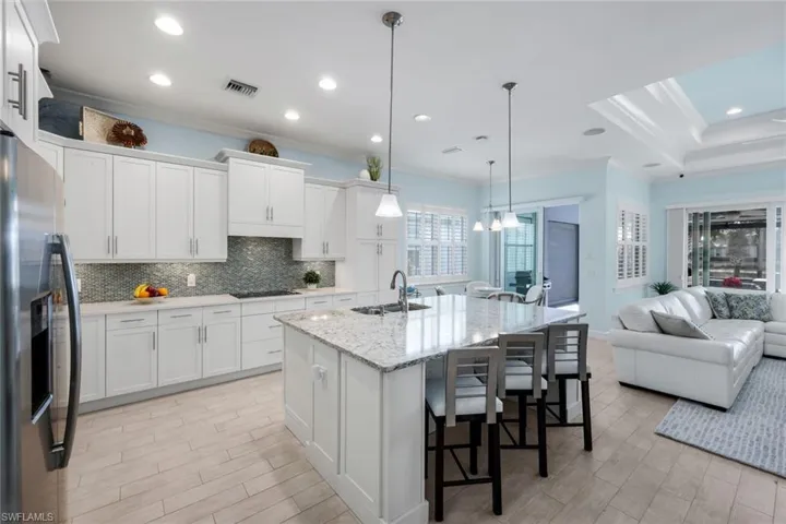 Kitchen with ornamental molding, white cabinets, a kitchen breakfast bar, wood finish floors, and light stone countertops