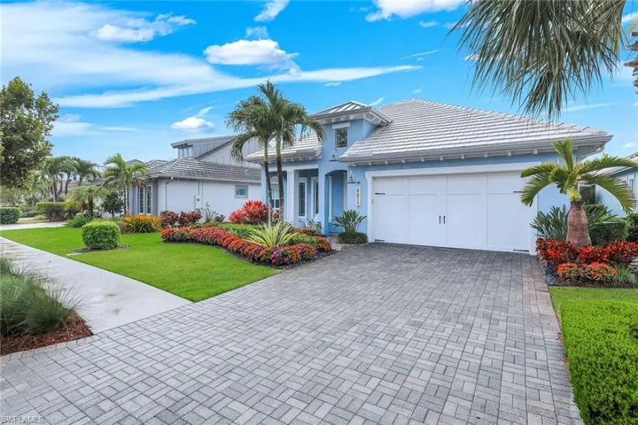 Ranch-style home featuring a front lawn, an attached garage, driveway, stucco siding, and a tile roof