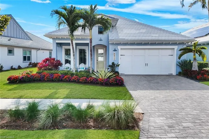 View of front of property featuring a front yard, decorative driveway, a garage, and stucco siding