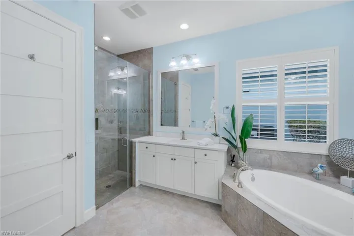 Bathroom featuring a shower stall, a garden tub, vanity, and recessed lighting