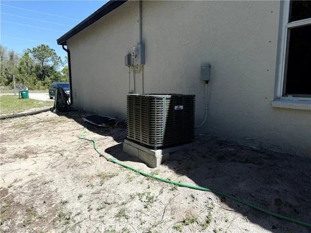 Details featuring stucco siding, central AC unit, and electric meter