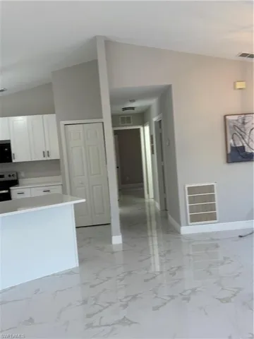 Kitchen featuring lofted ceiling, white cabinets, and range