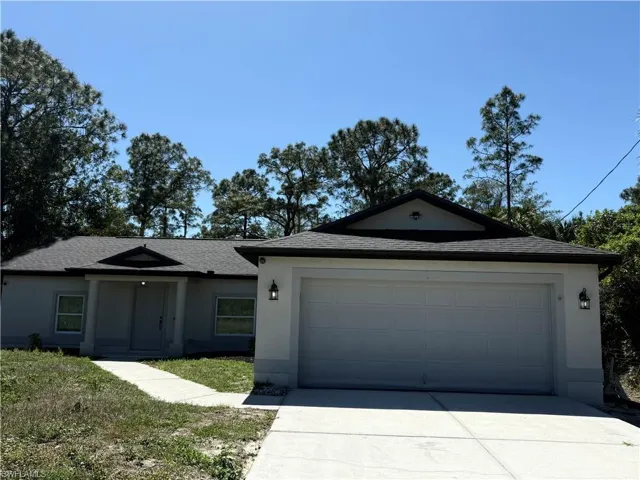 Single story home with a shingled roof, an attached garage, driveway, and stucco siding