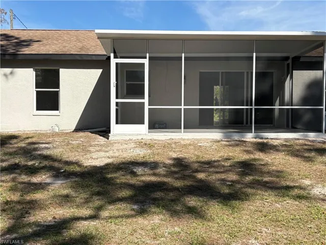 Back of property featuring a sunroom and a lawn