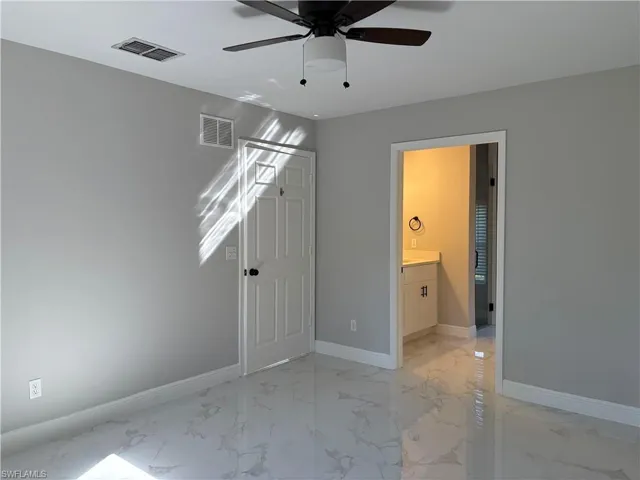 Unfurnished bedroom featuring ceiling fan and ensuite bath