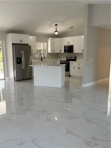 Kitchen featuring white cabinetry, a wealth of natural light, fridge, and range